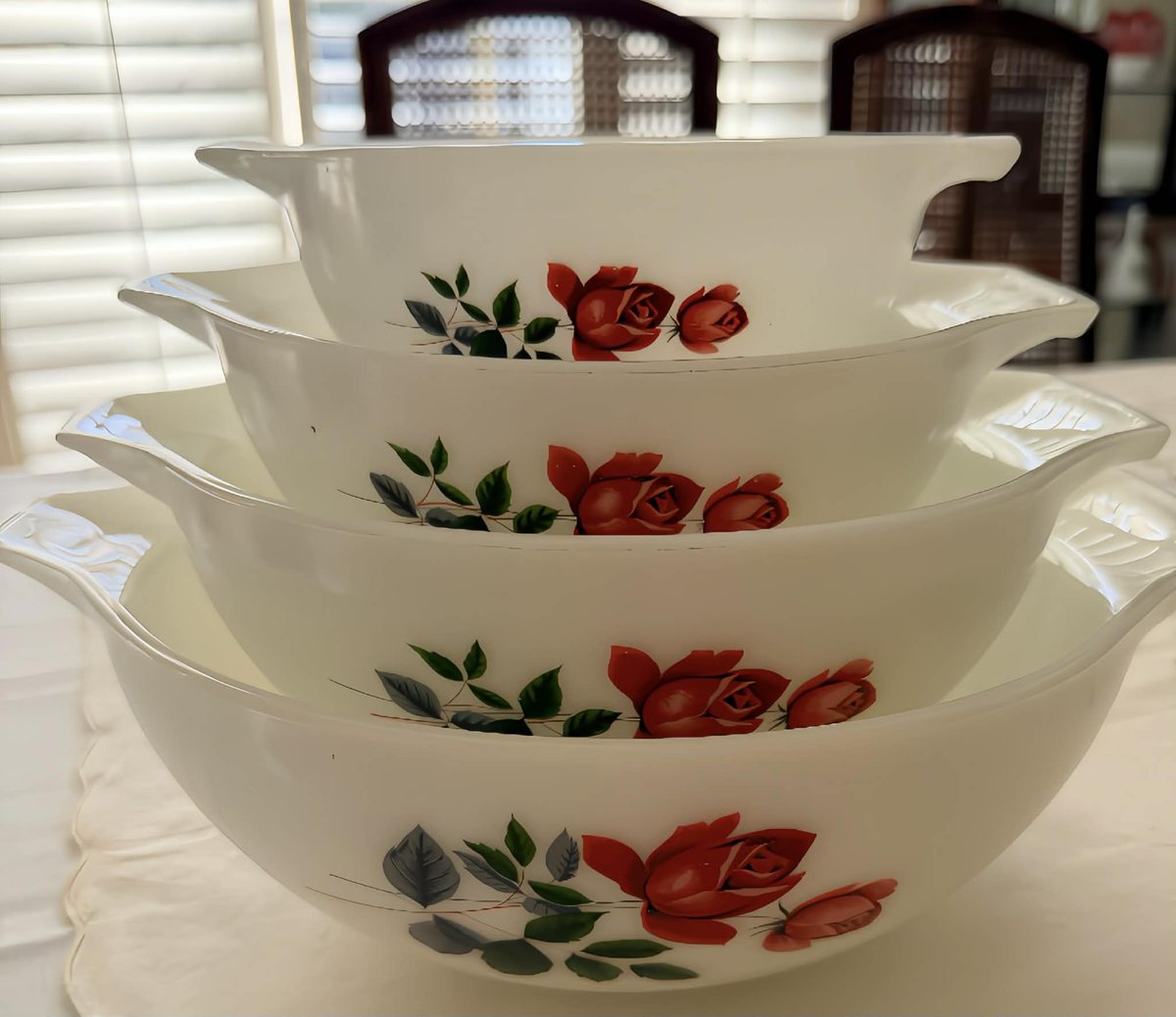 Four nesting white milk glass bowls with a red rose pattern
